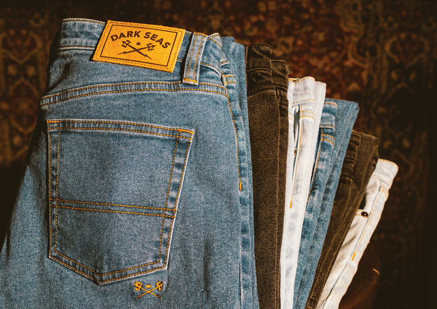 Denim pants folded and stacked on top of one another, faded blue and black colors.